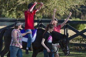 hippotherapy child on horse arms raised
